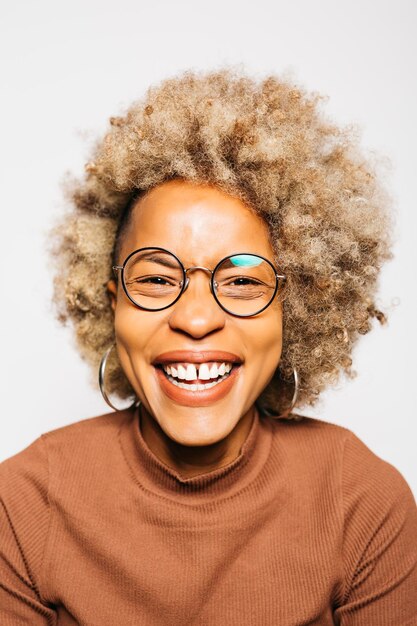 Retrato de mujer joven sonriente vistiendo ropa marrón mientras está de pie contra el fondo blanco.