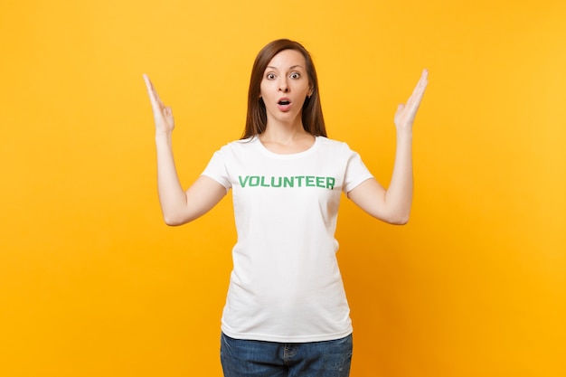 Retrato de mujer joven sorprendida molesta triste en camiseta blanca con voluntario de título verde inscripción escrita aislado sobre fondo amarillo. Ayuda de asistencia gratuita voluntaria, concepto de trabajo de gracia de caridad.