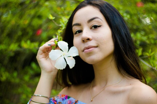 Foto retrato de una mujer joven sosteniendo una flor