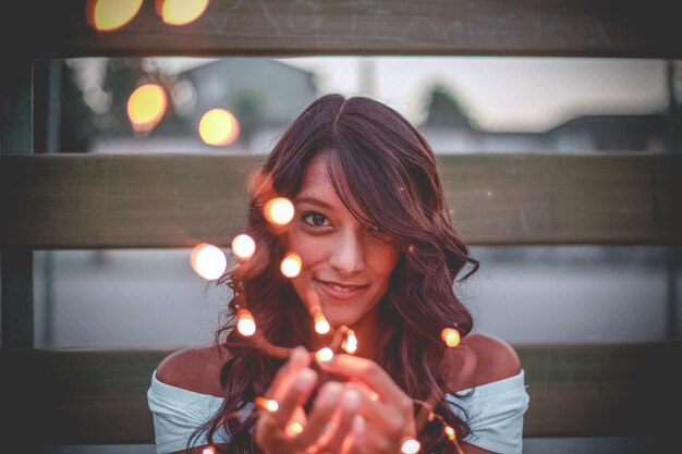 Foto retrato de una mujer joven sosteniendo una luz de cuerda iluminada