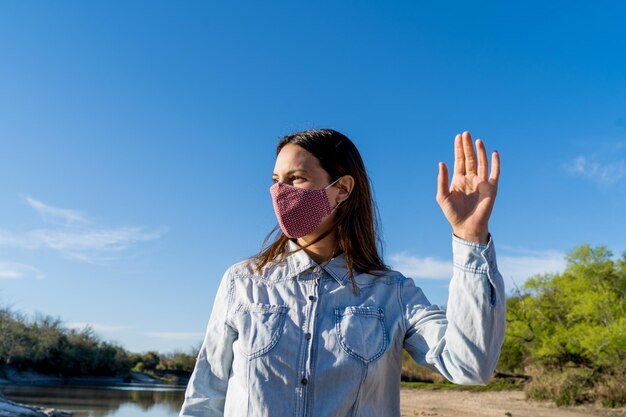 Foto retrato de una mujer joven con su máscara protectora en la playa