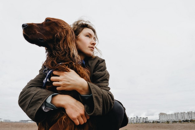 Retrato de una mujer joven con su perro. Perro setter irlandés en brazos de la amante amante.