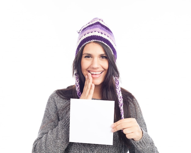 Retrato de una mujer joven con un suéter y un sombrero peruano de lana con una tarjeta de señal.