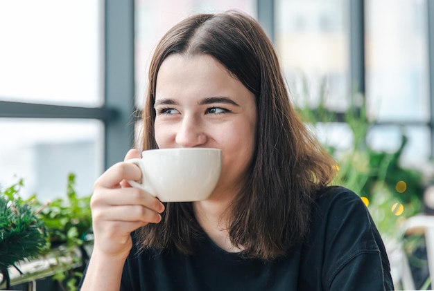 retrato, de, un, mujer joven, con, un, taza de té, en, un, café