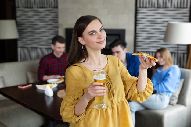 Retrato, de, un, mujer joven, tenencia, pizza, y, cerveza, en, un, pub