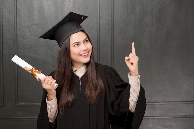 Retrato de mujer joven en toga de graduación sonriendo y animando