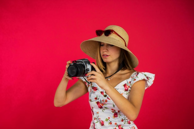 retrato de una mujer joven tomando fotografías con su cámara digital mientras está de pie en un estudio con fondo rojo