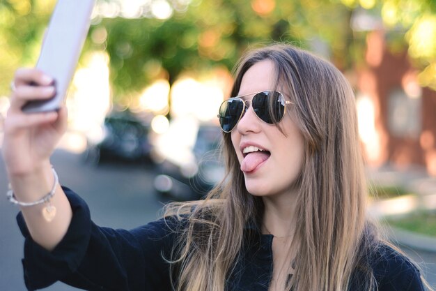 Retrato de mujer joven tomando selfie.