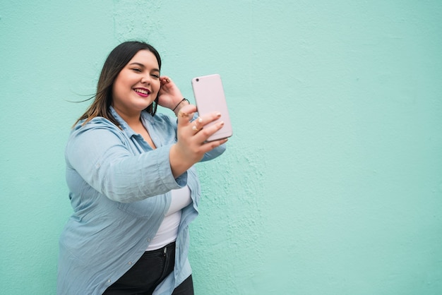 Retrato de mujer joven tomando selfies con su teléfono mophile al aire libre