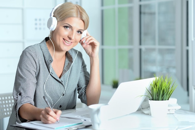 retrato, de, mujer joven, trabajando, con, computador portatil, en, oficina