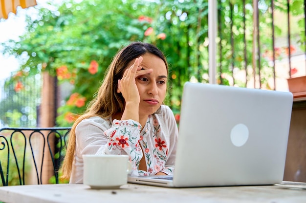 retrato de una mujer joven trabajando en su portátil con una mirada preocupada en su cara
