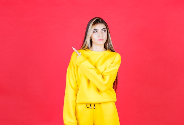 Retrato de mujer joven en traje amarillo apuntando a algún lugar