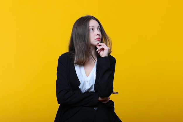 Retrato de una mujer joven en un traje de negocios sobre un fondo amarillo