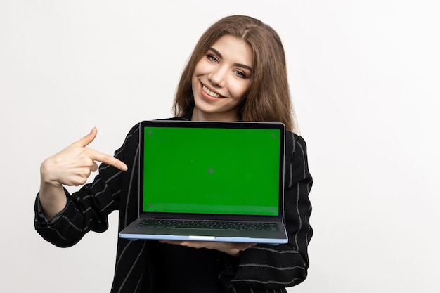 Retrato de una mujer joven en traje sobre un fondo blanco Una mujer de negocios con una llave de croma de portátil La modelo señala con el dedo el cuaderno
