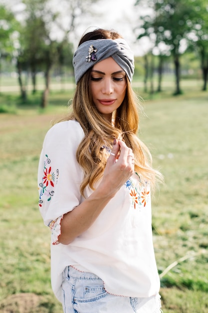 Retrato de mujer joven con turbante en la cabeza y posando al aire libre en el parque