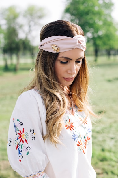 Retrato de mujer joven con turbante en la cabeza y posando al aire libre