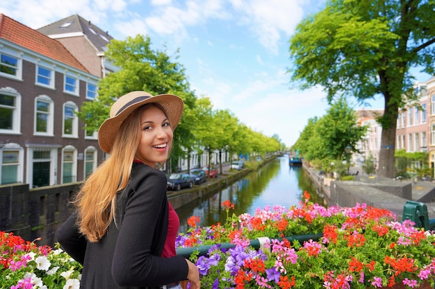 Retrato de mujer joven turista entre macetas mirando a la cámara en el canal en La Haya, Países Bajos