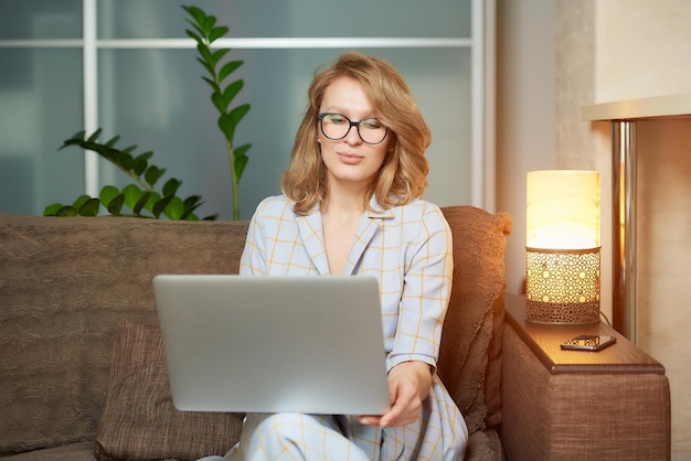 Retrato de una mujer joven usando una computadora portátil en casa