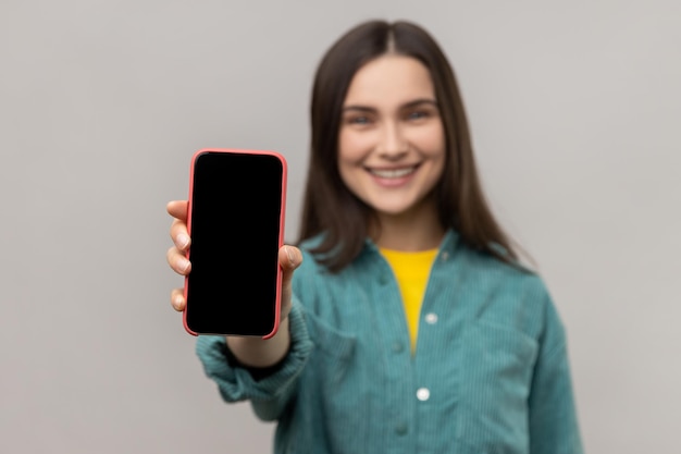 Foto retrato de una mujer joven usando un teléfono móvil contra la pared