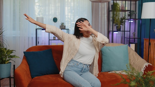 Foto retrato de una mujer joven usando el teléfono móvil mientras está sentada en el sofá en casa