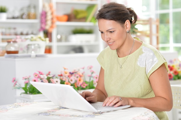 retrato, de, mujer joven, usar la computadora portátil, en, cocina