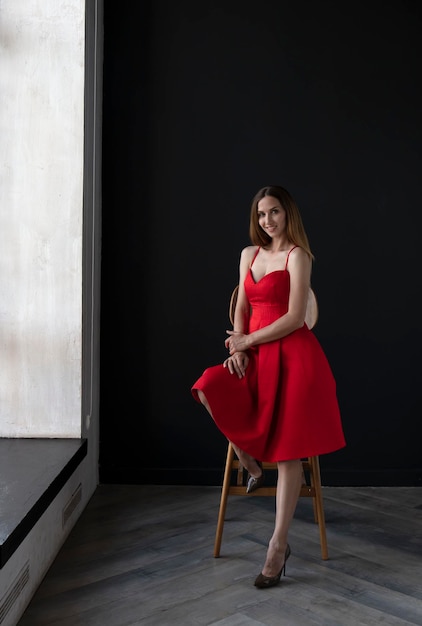 retrato, de, un, mujer joven, en, un, vestido rojo, sentado, en, un, taburete alto, de la barra