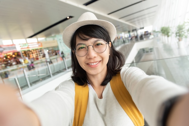 Retrato de mujer joven viajero usar gafas y sombrero tomando selfie.