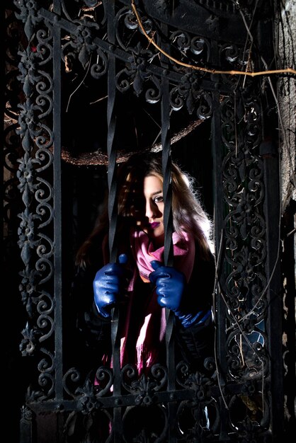 Foto retrato de una mujer joven vista a través de la puerta por la noche