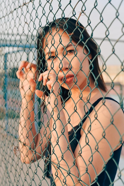 Foto retrato de una mujer joven vista a través de una valla de cadena