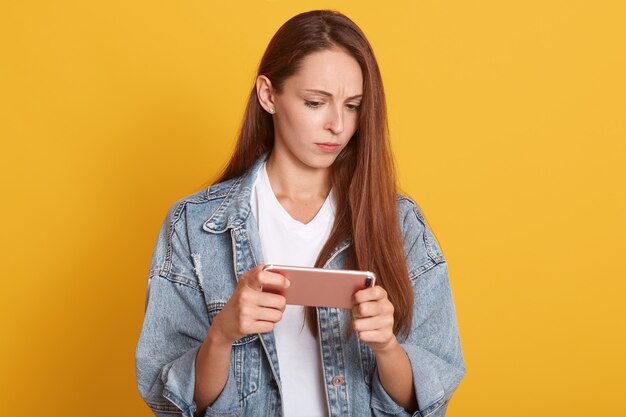 Retrato de mujer joven vistiendo ropa casual de mezclilla con teléfono móvil