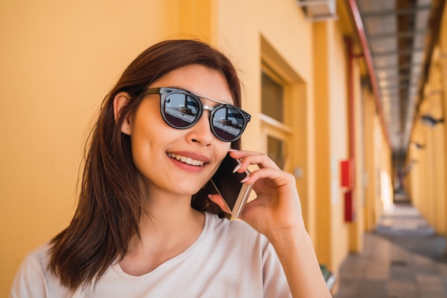 Retrato de mujer latina joven hablando por teléfono al aire libre en la calle. Concepto urbano.