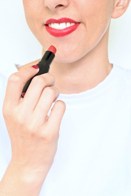 Retrato de mujer latina joven irreconocible pintando sus labios rojos