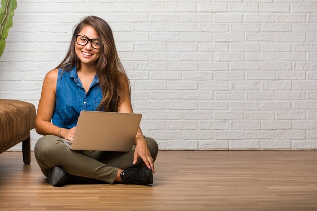 Foto retrato de una mujer latina joven sentada en el piso alegre y con una gran sonrisa