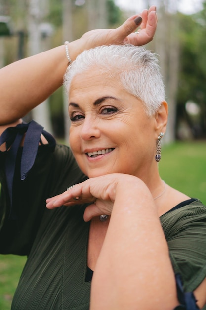 Foto retrato de una mujer latina mayor riendo mira a la cámara con confianza en un parque