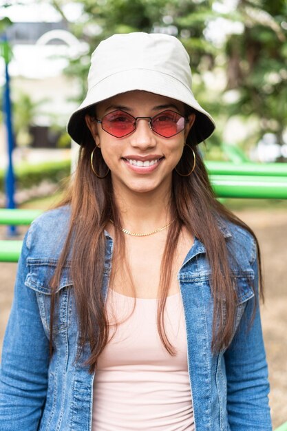 Retrato de mujer latina mirando a la cámara con gafas de sol rojas