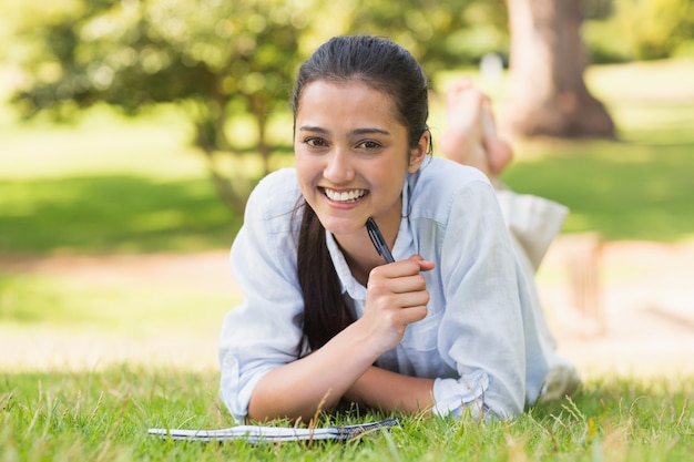 Retrato de una mujer con libro y pluma en el parque