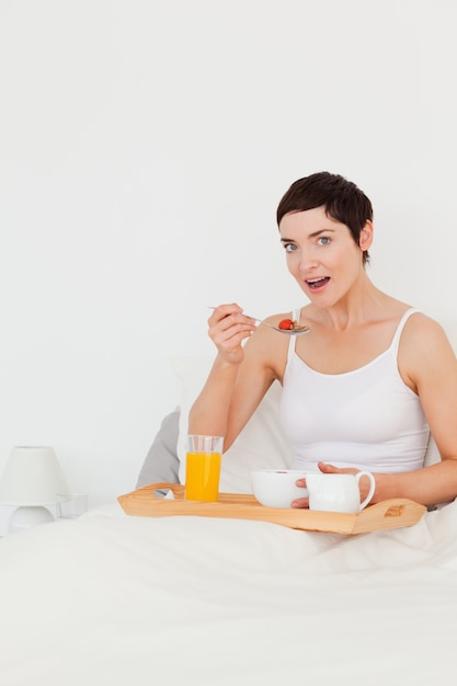 Retrato de una mujer linda comiendo cereal mientras mira a la cámara