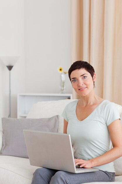 Retrato de una mujer linda que trabaja con una computadora portátil