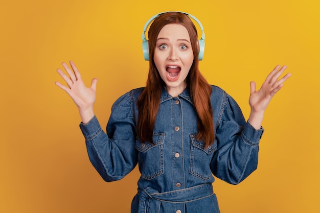 Retrato de mujer loca funky usar auriculares escuchar música levantar palmas gritar boca abierta sobre fondo amarillo