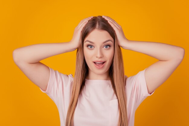 Retrato de mujer loca sin palabras manos cabeza boca abierta sobre fondo amarillo