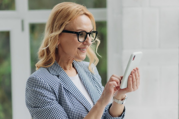 Retrato mujer madura de 50 años mayor cliente femenino de mediana edad con smartphone mediante aplicación móvil