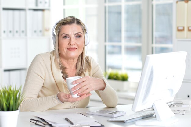 retrato, de, mujer madura, en, auriculares, bebida, té