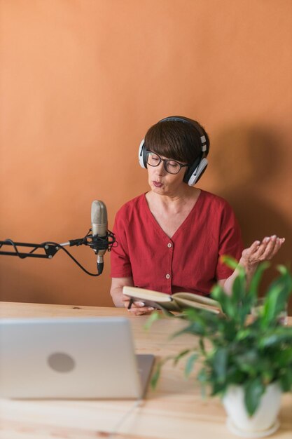 Foto retrato de mujer madura con auriculares y hablando en el podcast de la estación de radio en línea y