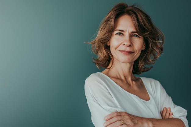 Retrato de una mujer madura con los brazos cruzados sobre un fondo azul.