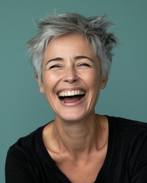 Retrato de una mujer madura feliz con el pelo gris corto riendo sobre fondo azul foto de archivo