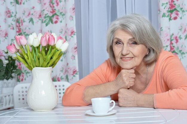 Retrato de mujer madura con flores bebiendo té