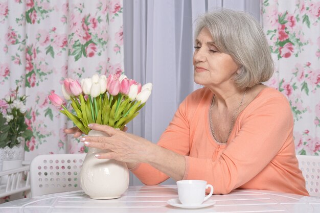 Retrato de mujer madura con flores bebiendo té