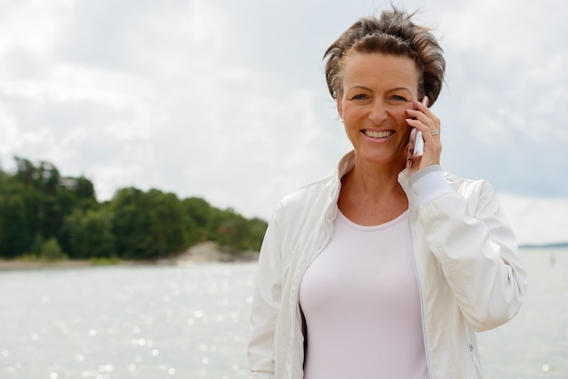 Retrato de mujer madura hermosa contra la vista panorámica del lago y el cielo en la naturaleza