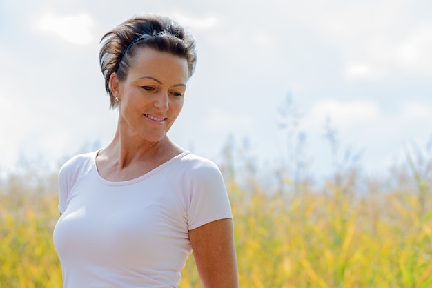 Retrato de mujer madura hermosa relajante en los campos de hierba alta en la naturaleza