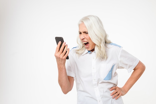 Retrato de una mujer madura loca gritando en el teléfono móvil